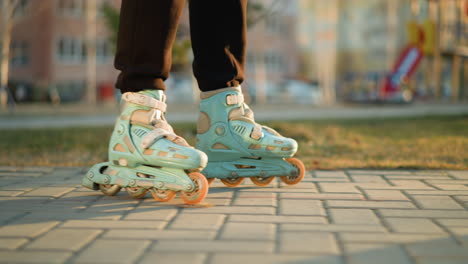 side shot focusing on a person s feet wearing rollerblades as they glide smoothly along a paved path in a park. the motion of the rollerblades, with a green and urban background subtly blurred