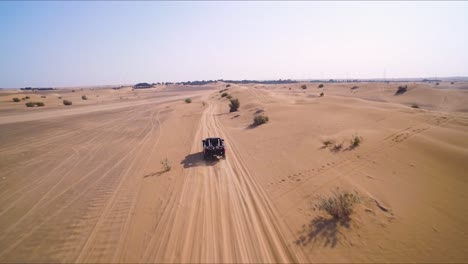 black 4x4 truck races down an off-road path near sand dunes in the desert outside of dubai, uae