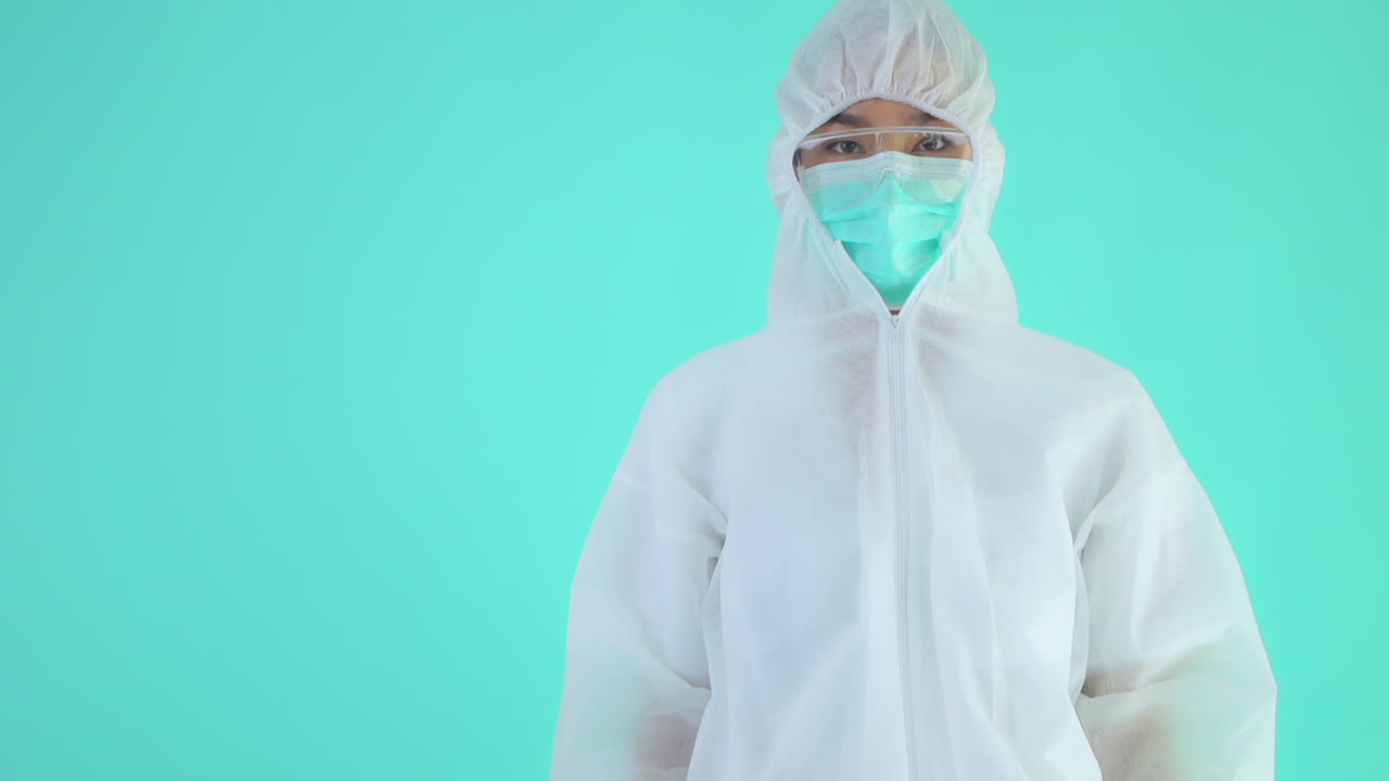Portait of Medical Person in Virus Protective Clothing Showing Thumb Up. Isolated on Turquoise Background
