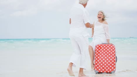 barefoot mature caucasian couple with suitcase and camera