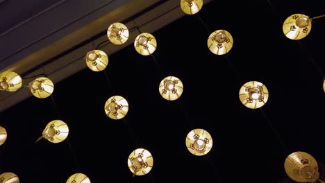 farolillos amarillos colgando en el aire iluminando la ciudad en una noche oscura, tiro inclinado hacia arriba