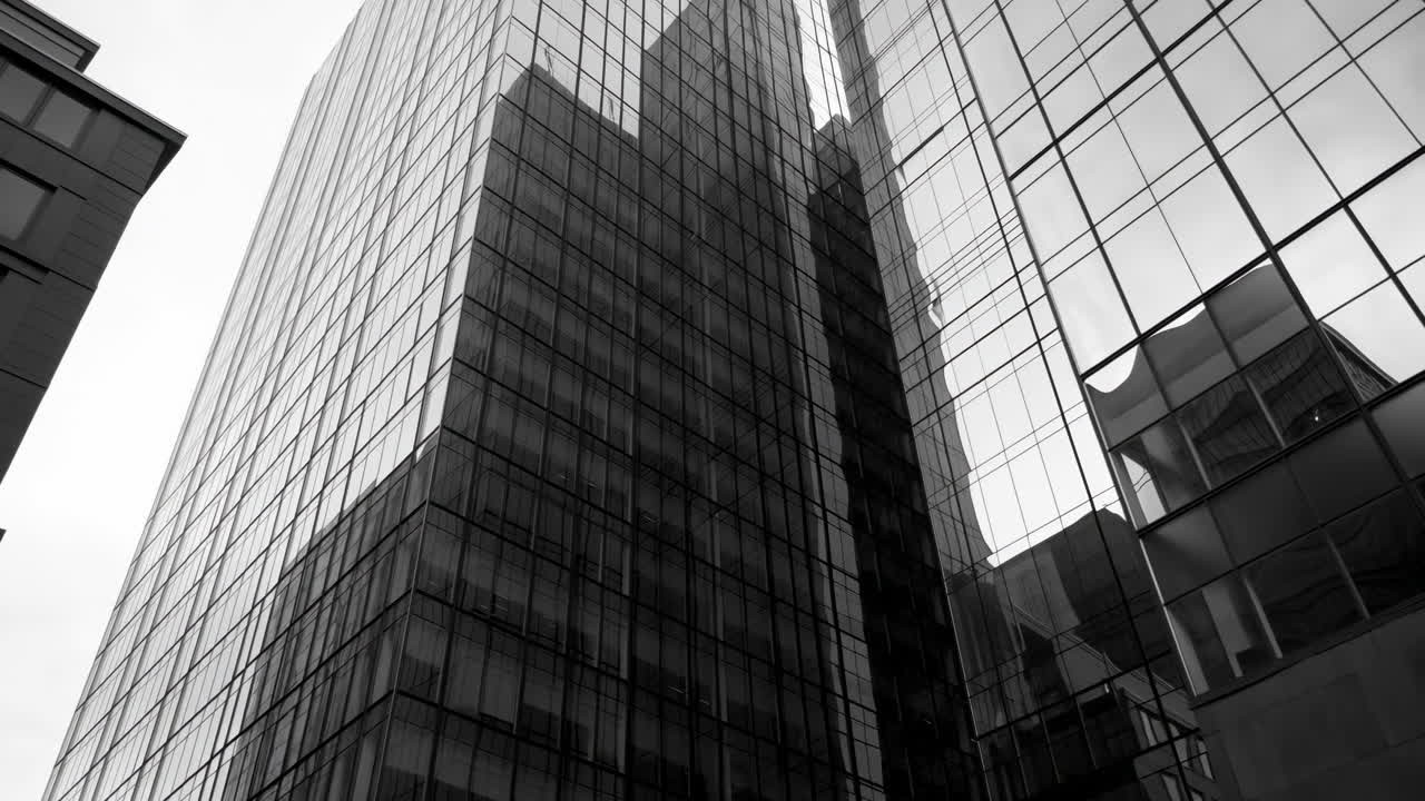 Barrido ascendente en ángulo bajo de un rascacielos moderno de cristal en monocromo
