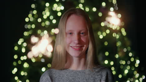 happy child holding sparklers, standing against the backdrop of a christmas tree at home