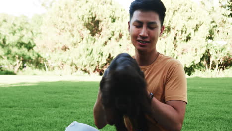 asian man playing with dog in park, enjoying sunny day outdoors