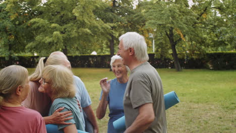 sporty elderly people greeting female trainer in park