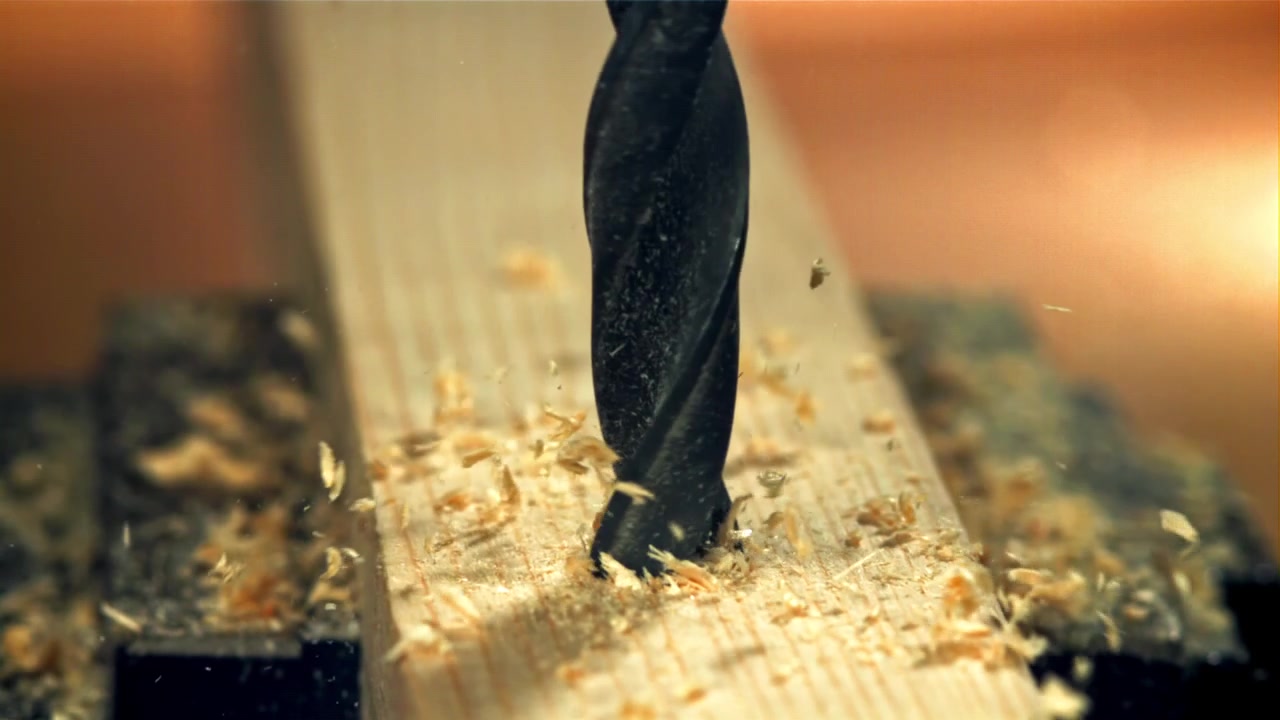 Close-up of a Drill Bit Making a Hole in Wood with Flying Shavings