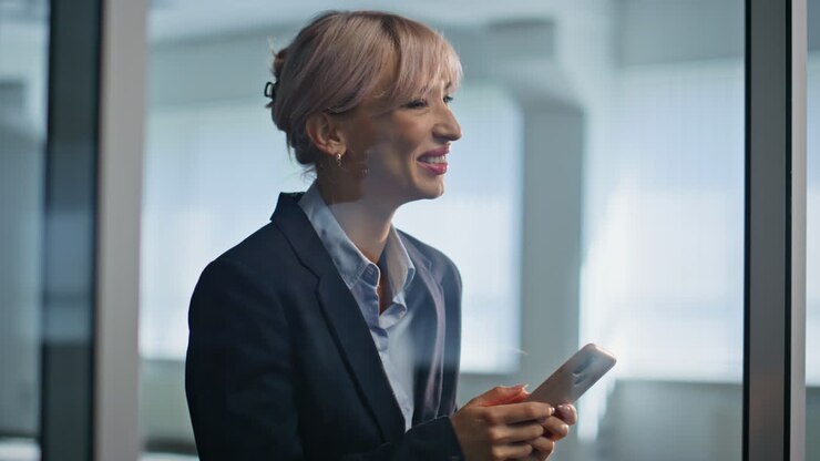 Happy lady reading message on mobile phone inside modern office building closeup