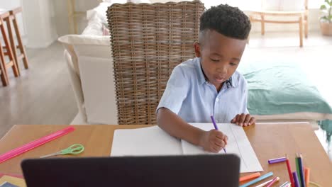 happy african american boy using laptop for online class at home, slow motion