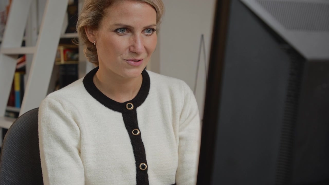 Young businesswoman using her mouse to browse the Internet and working in her home office