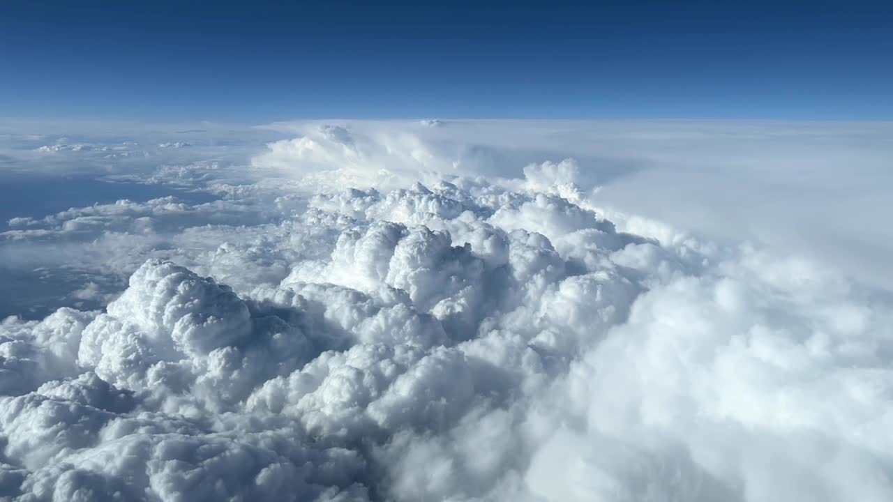 Veduta aerea scattata dalla cabina di pilotaggio di un jet di alcuni enormi cumulonembi a quota di crociera durante il giorno.