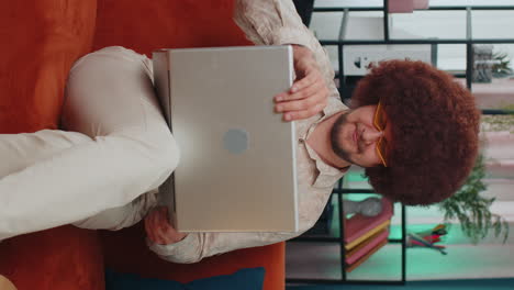 Young-man-freelancer-sitting-on-sofa-closing-laptop-pc-after-finishing-work-in-living-room-at-home