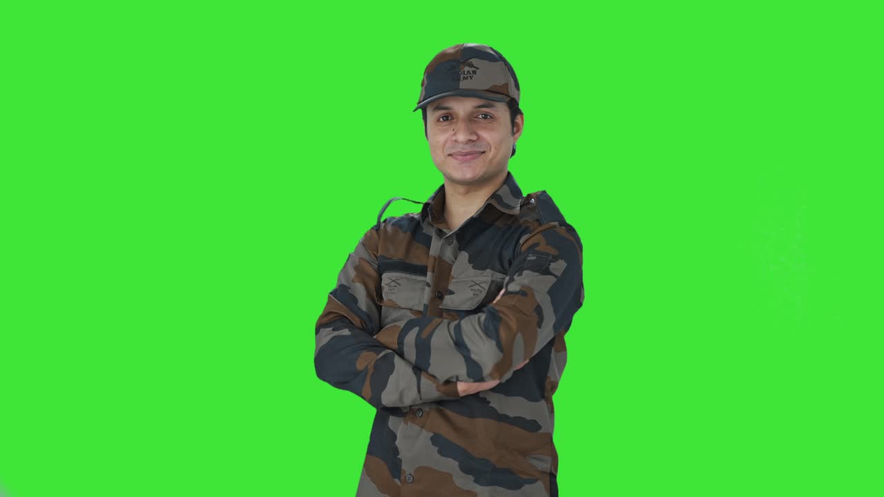 Retrato de militar indiano feliz com os braços cruzados em fundo verde
