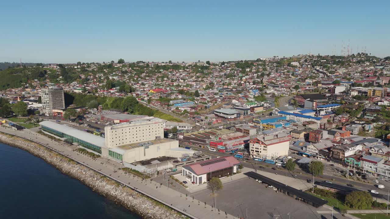 Aerial view of Puerto Montt in Chile, featuring the waterfront area, cityscape rising on the hills, and the Reloncavi Sound on a sunny day. pull back shot