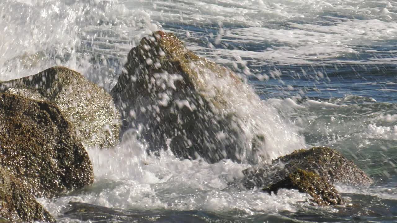 Onda che si infrange sulle rocce in uno spruzzo bianco, primo piano