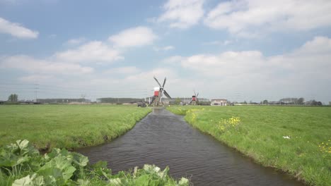 landscape with traditional windmills at a pond in a green meadow - wide shot