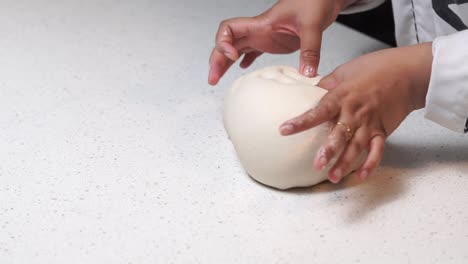 kneading white dough with hands on white table slow motion ready wide shot