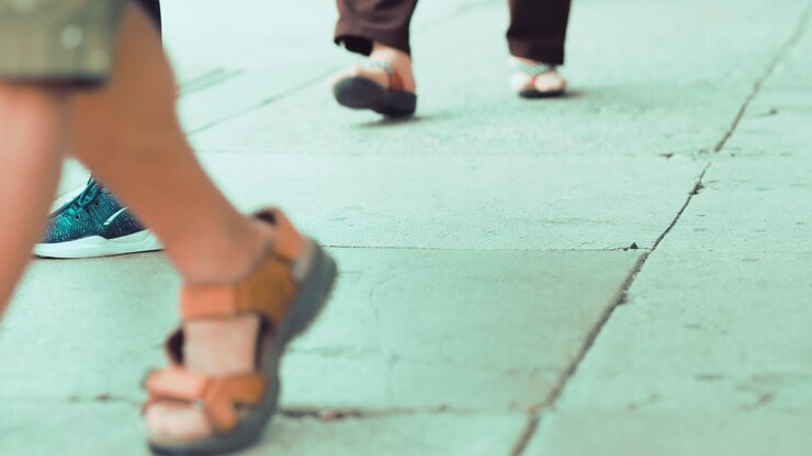 People wearing sandals and flip flops walking on the sidewalk
