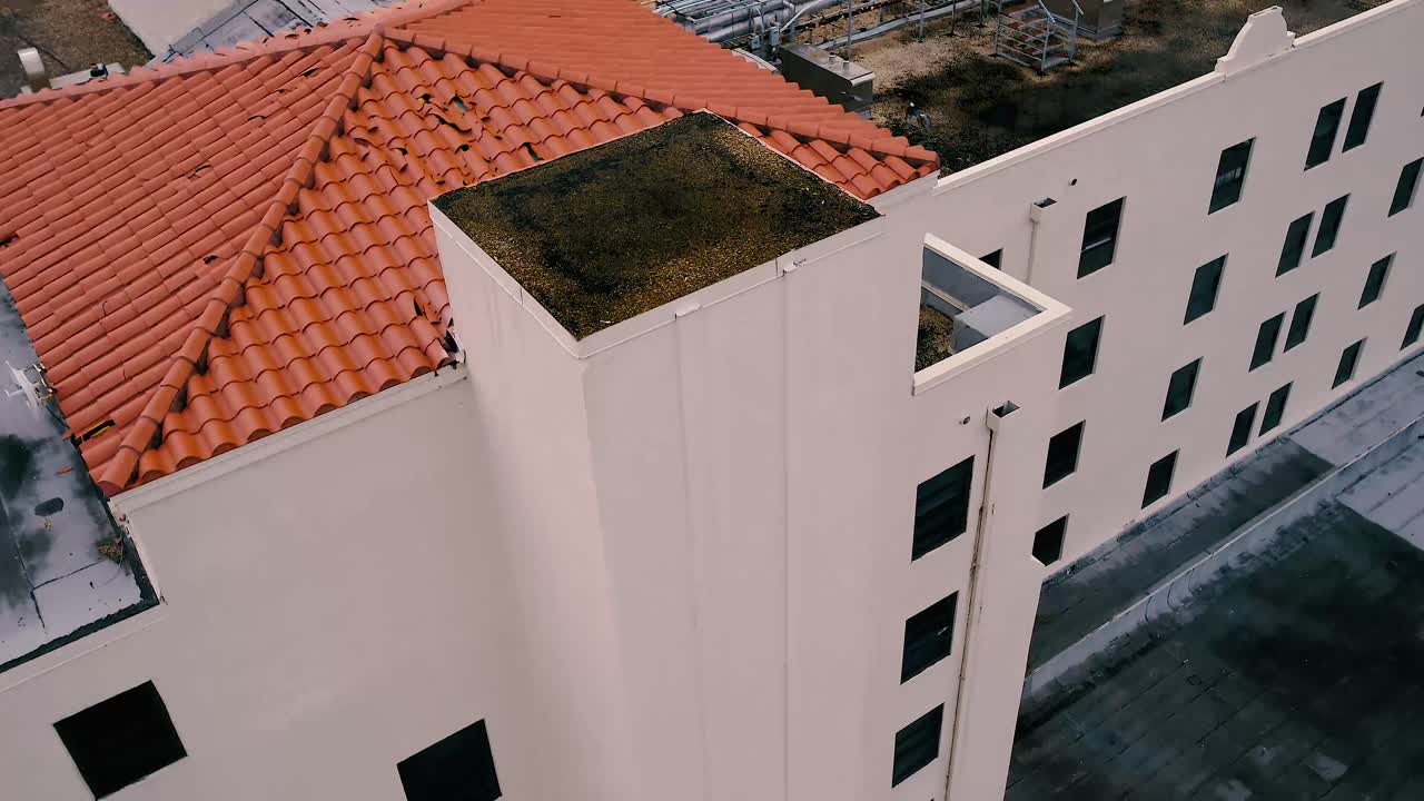 Rise from ground to the top of a building to see damaged Spanish tile