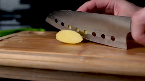 close up shot of a silver knife chopping a potatoe, camera slides