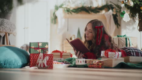 Hermosa-Mujer-Leyendo-Un-Libro-En-El-Suelo-Durante-La-Navidad-En-Casa