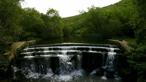 aerial footage of a landscape photographer, tourists admiring a waterfall in the derbyshire peak district national park near bakewell