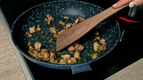 tirando trozos de pollo frito en una sartén antiadherente, primer plano