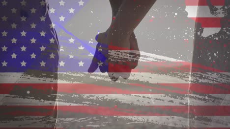 american flag with glitch effect against mid section of couple holding hands at the beach