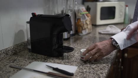 Kitchen-countertop-with-a-black-coffee-machine,-a-small-espresso-cup,-and-a-cutting-board-with-a-knife