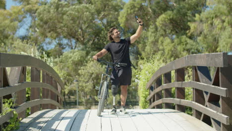 una foto larga de un motociclista con discapacidad tomando una selfie en un parque de verano