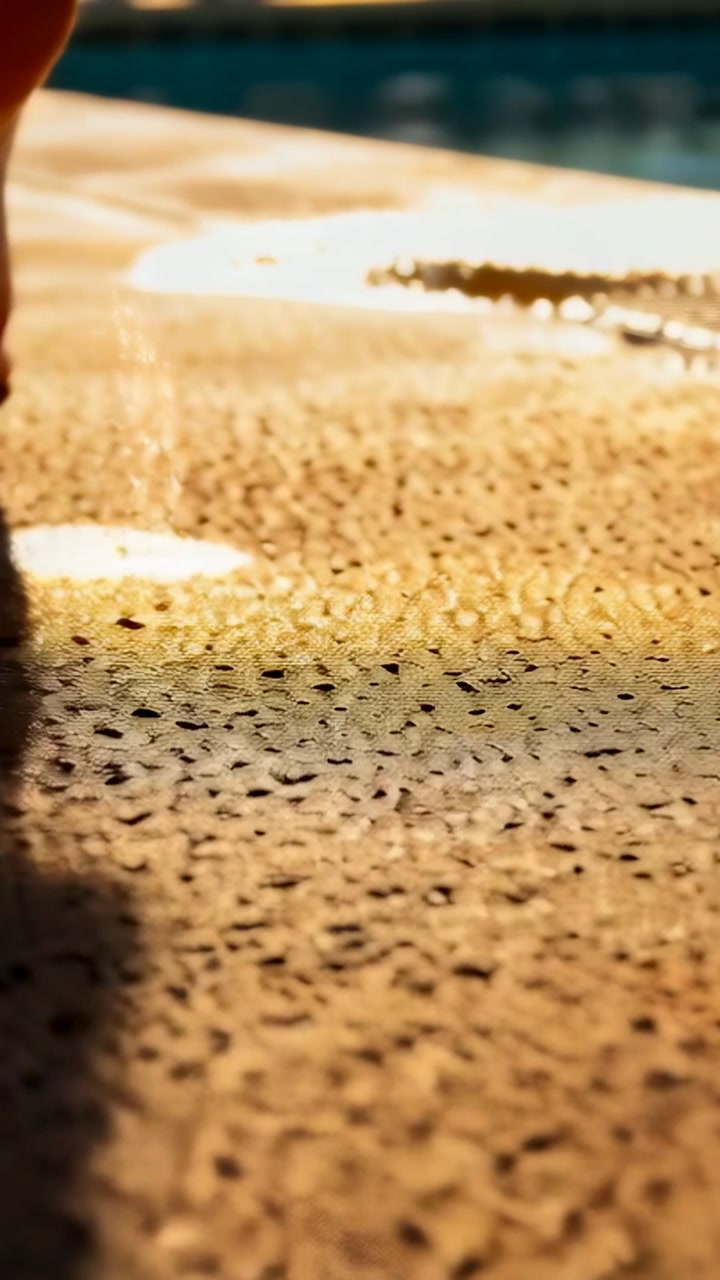 Vertical video: Walking barefoot man toes touching pool deck, pressing and rolling, puddles shining