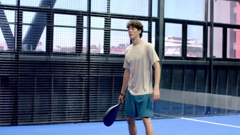 man playing padel tennis on indoor court, holding racket and focusing on game