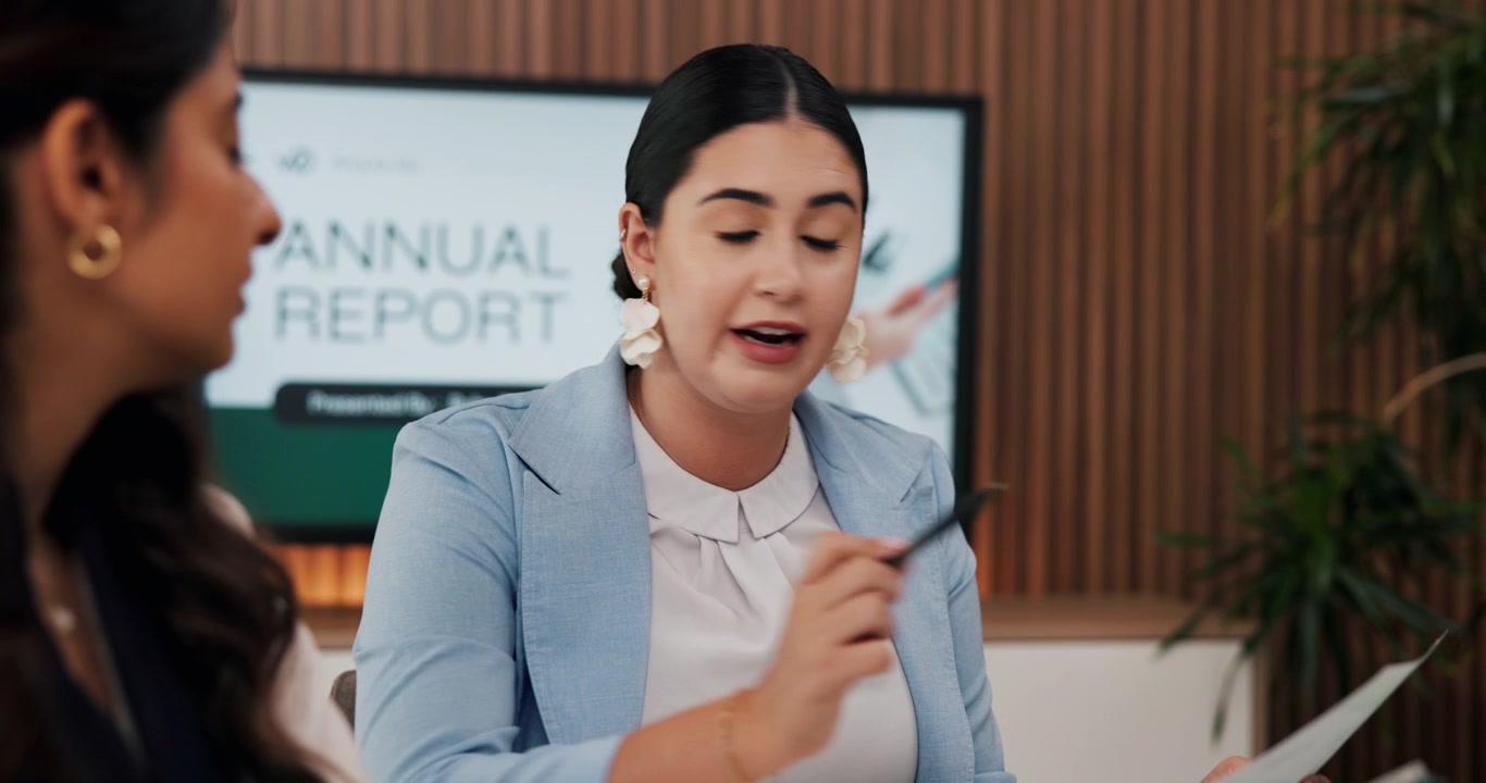 Businesswoman Discussing Annual Report with Colleague in Office