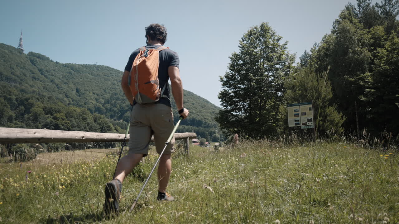 Un uomo con uno zaino cammina con i bastoncini verso il monte Boč.