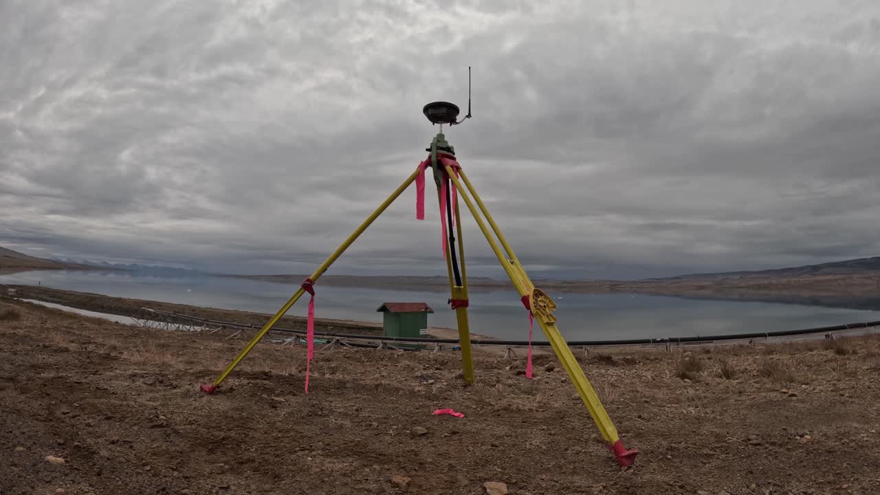 Tidsforløb af en GNSS-opmålingsbasestation centreret i billedet i Eureka, Nunavut, Canada. Ishavet i baggrunden med rullende skyer over hovedet over et koldt, goldt højarktisk landskab