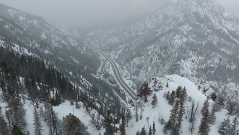 wild alpine trees on copper mountains covered in snow with roads passing by frisco in colorado, usa. drone shot.