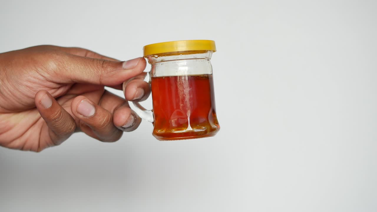 Hand holding a small glass jar with a yellow lid