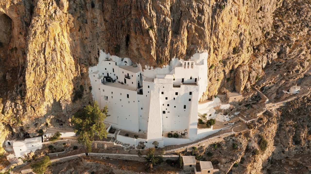 Panagia Chozoviotissa Monastery glows at sunrise on rugged cliffs of Amorgos Island, Greece