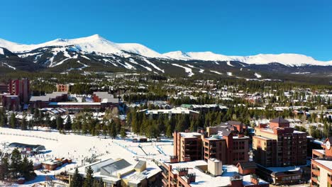 hotels and appartments in winter mountain town covered in snow with people skiing for holiday vacation