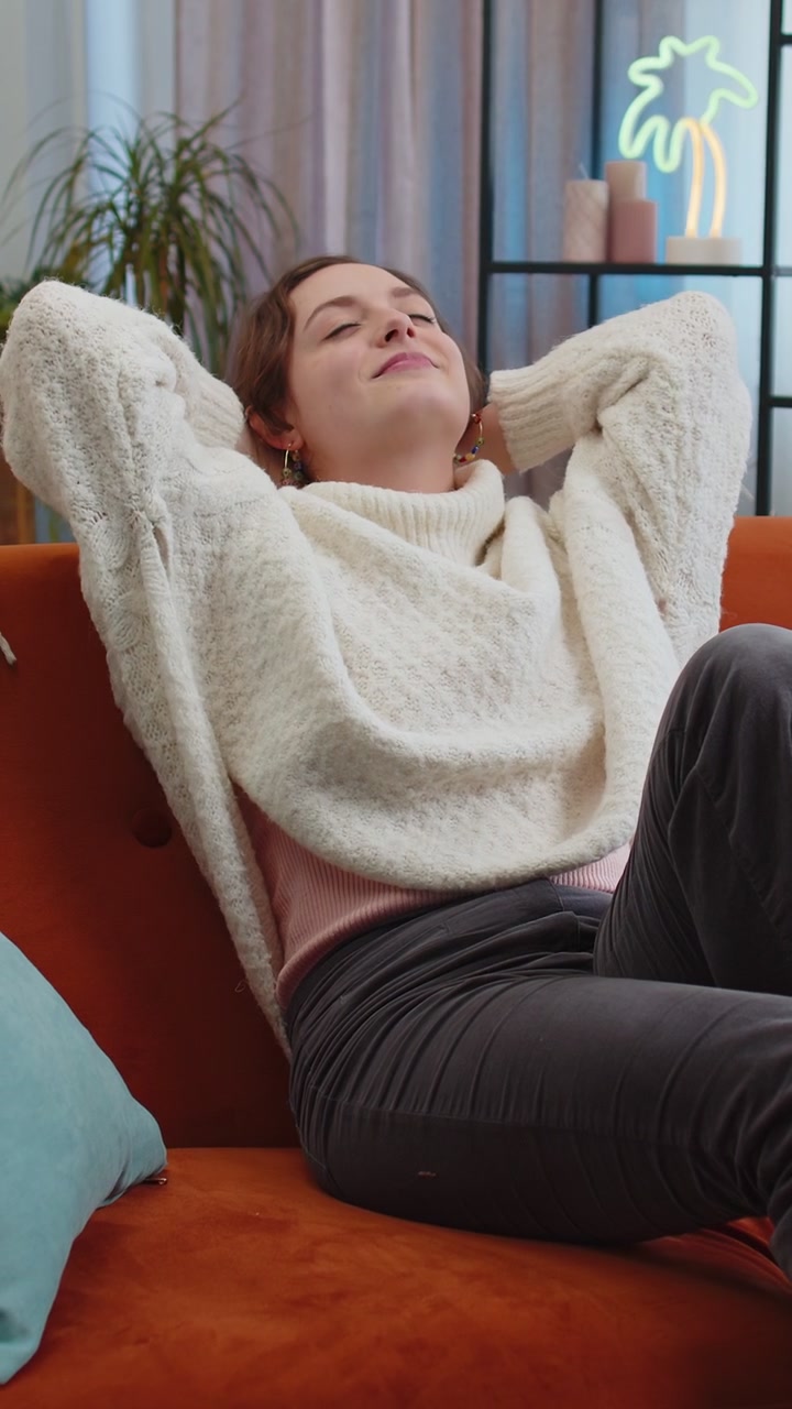 Una donna pigra e stanca si rilassa sul divano di casa, si riposa, fa un pisolino dopo una dura giornata di lavoro, chiude gli occhi.