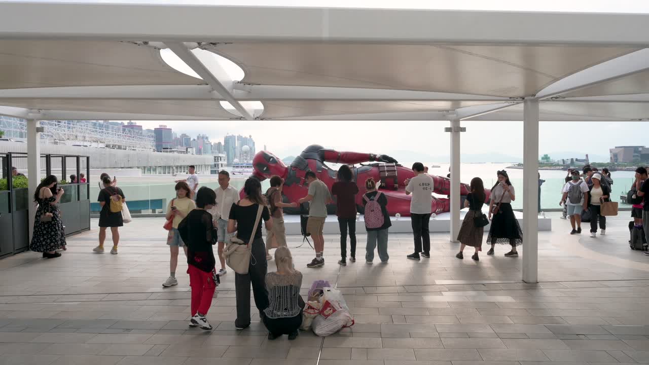 An 8-meter Deadpool installation in Hong Kong attracts locals and tourists for photos, with the skyline as a backdrop. The display promotes Disney’s "Deadpool and Wolverine" movie.