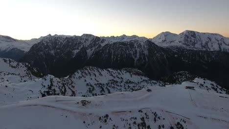 French-alps-at-Chamrousse-during-early-sunrise-approaching-the-ridge,-Aerial-flyover-shot