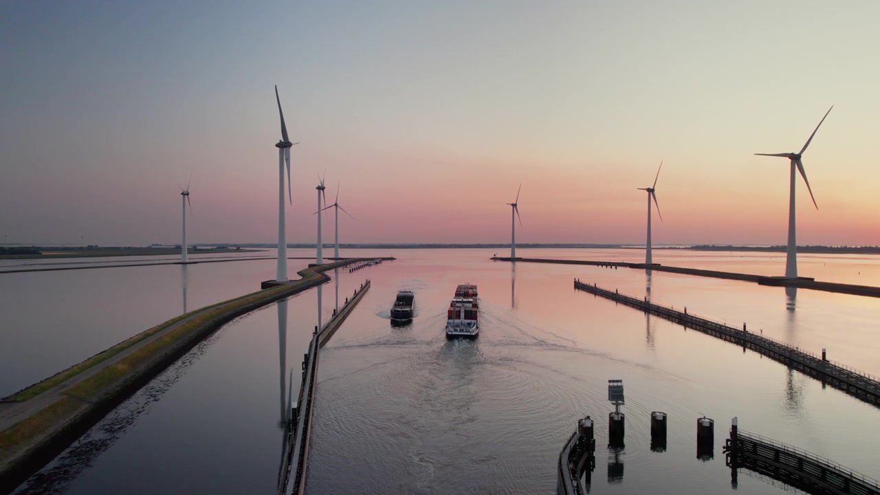 Flyfoto av lektere som seiler på Krammer-sjøen med vindturbiner under solnedgang i Bruinisse, Nederland.