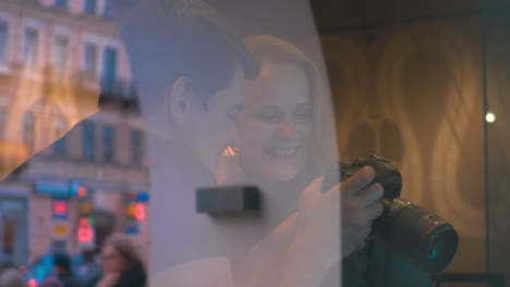 Man-and-woman-looking-at-photos-on-camera-in-cafe