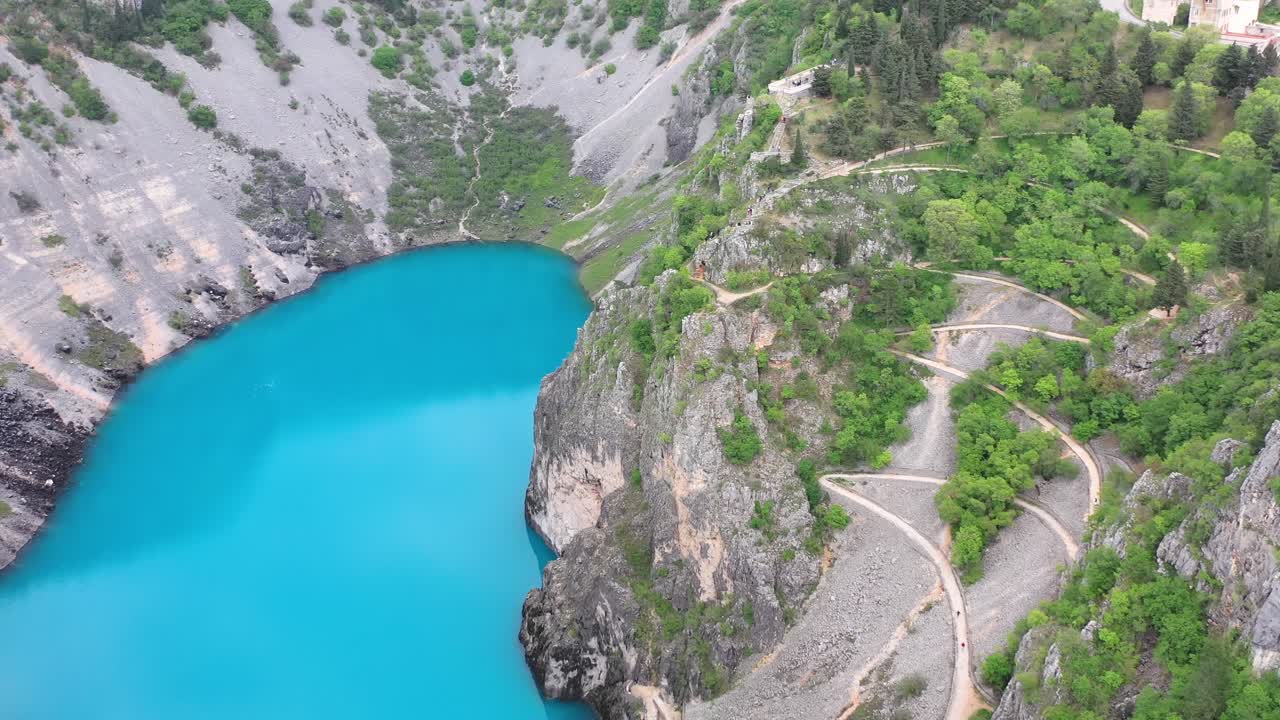 Imotski Blue lake, stunning winding road on cliff. Aerial backwards
