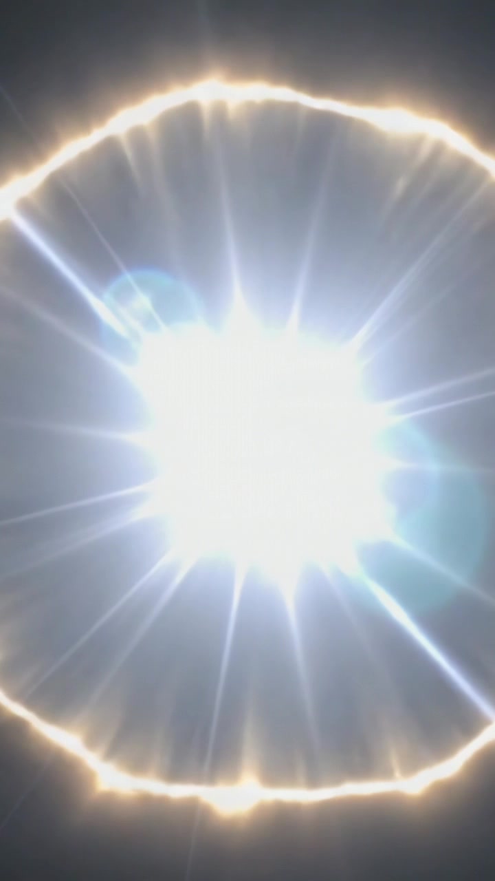 Vídeo vertical: Reflexo de luz enquanto a câmera se move, formando um halo de estrela e fantasmas de lente em campo escuro.