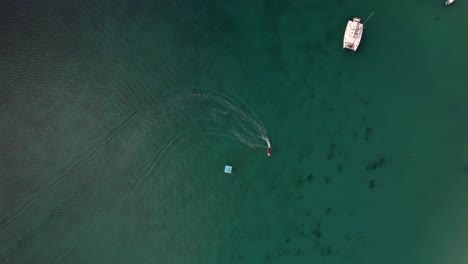 Drone-shot-of-speeding-jet-sky-and-yacht-at-beau-vallon-beach,-clear-water,-cinematic-colour