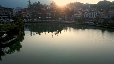 Aerial-Pan-Right-Over-Calm-Scenic-Sapa-Lake-In-Vietnam-With-Sunset-Seen-Behind-Mountains-In-The-Background