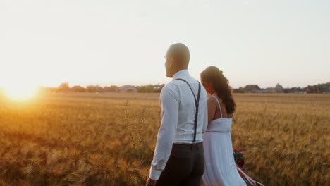 pareja caminando en un campo de trigo al atardecer