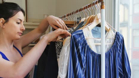 young woman selecting a dress from clothes rack 4k