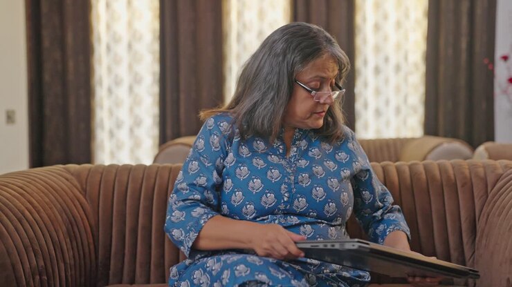 india envejecida cierra su computadora portátil después de las horas de trabajo